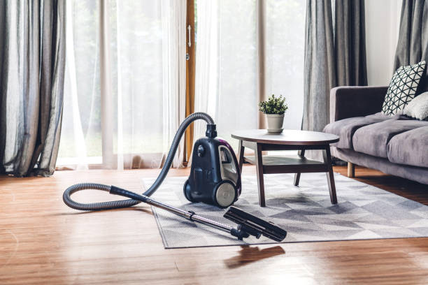 A tidy living room with a vacuum cleaner on the floor, ready for use as part of a 30-day cleaning checklist.